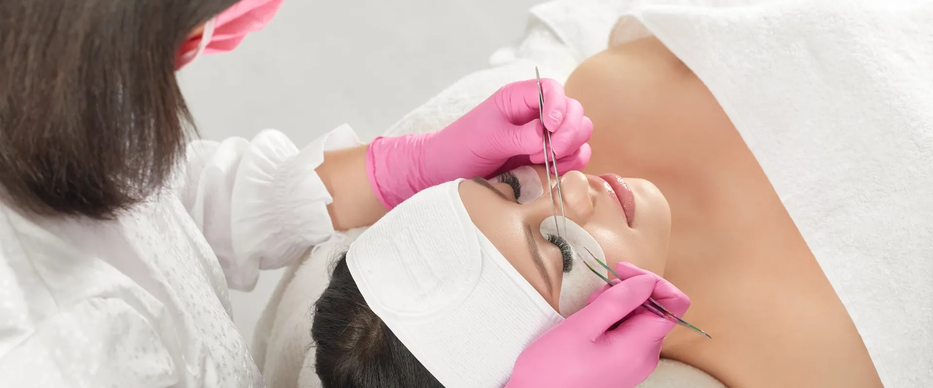 Brown lash extensions — Beautician applying eyelash extensions to a client